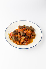 Braised beef with carrots and peppers in rich gravy on plate, isolated on white