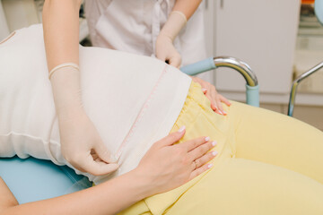 Pregnancy checkup. Gynecologist measures mother belly to assess the baby growth and development. Gynecologist tracks the baby growth by measuring the expectant mother belly size at prenatal visit.