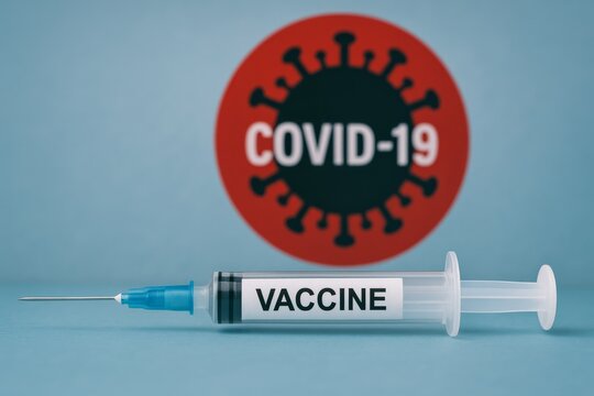 Syringe labeled "VACCINE" lies before a red circle with "COVID-19" on a blue backdrop. Concept of immunization, safety, prevention. For health article photo