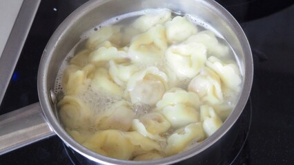 Tortellini with parmesan, ready to eat, Italian ravioli pasta with spinach and ricotta on white table, traditional italian food with herbs and vegetables