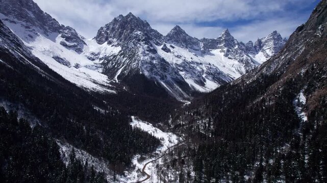 Drone view of snow covered mountains and forests in Bipeng Valley in Sichuan, China in sunny winter day, high angle view of beautiful winter landscape. 4k real time footage, travel concept