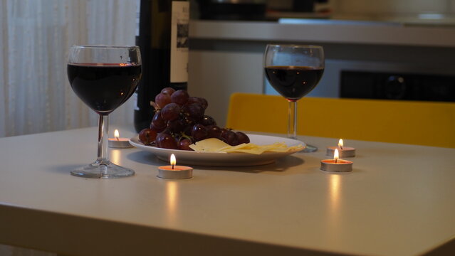 Romantic couple enjoying dinner at home, concept love, relationship and romantic, happy couple celebrating and making cheers with glasses of red wine. girl eats grapes and cheese, Valentine's Day