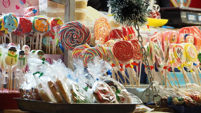 Sweets and drinks at the Christmas market. Stylish christmas illumination and fir branches with red and gold baubles, golden lights bokeh on front of building at holiday market in city street.Christma