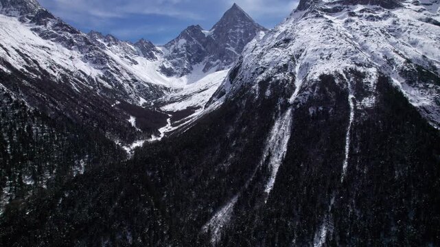 Drone view of snow covered mountains and forests in Bipeng Valley in Sichuan, China in sunny winter day, high angle view of beautiful winter landscape. 4k real time footage, travel concept