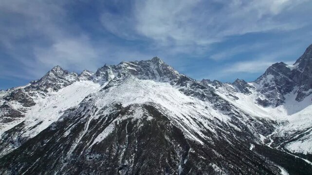 Drone view of snow covered mountains and forests in Bipeng Valley in Sichuan, China in sunny winter day, high angle view of beautiful winter landscape. 4k real time footage, travel concept