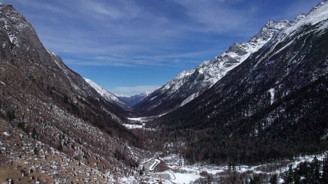 Drone view of snow covered mountains and forests in Bipeng Valley in Sichuan, China in sunny winter day, high angle view of beautiful winter landscape. 4k real time footage, travel concept