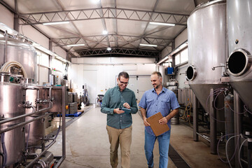 Brewery workers discussing production while inspecting facility