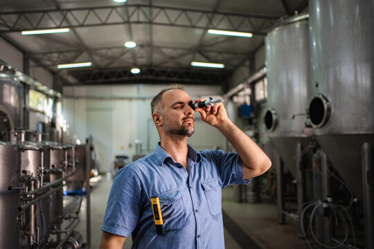 Brewer performing quality control with refractometer in brewery - Powered by Adobe