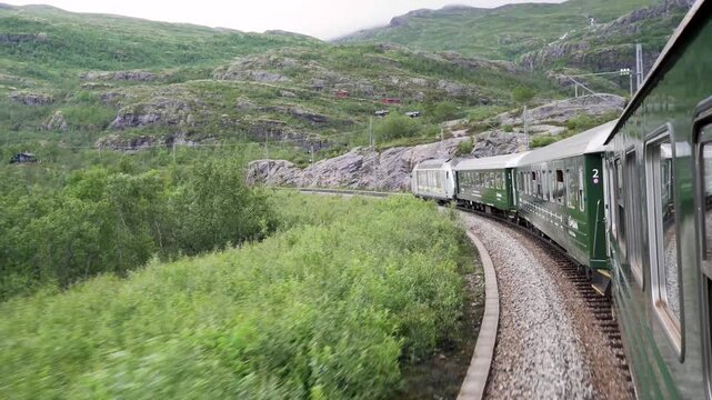The Fl&aring;msbana train in Norway as it travels through lush green mountains and waterfalls view from inside a carriage. Smooth cinematic motion and authentic nature atmosphere