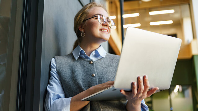 Young woman working on laptop in modern workspace - Powered by Adobe