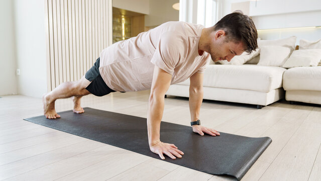 Man practicing push-ups on a yoga mat indoors