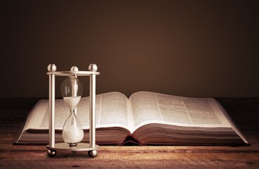 Naklejka premium Sandglass with ancient book. History concept