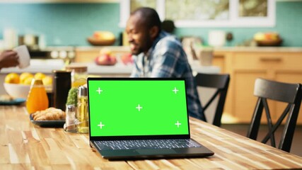 Green screen mockup on laptop next to African American couple relaxing at home, drinking coffee and serving croissants. Cozy breakfast scene with healthy food for a balanced lifestyle. Camera B. - Powered by Adobe