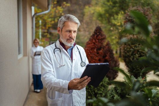 Doctors using digital tablet outdoors for patient care