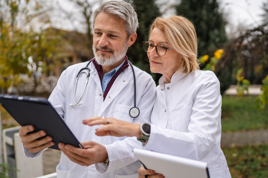 Medical team collaborating discussing patient records outdoors - Powered by Adobe