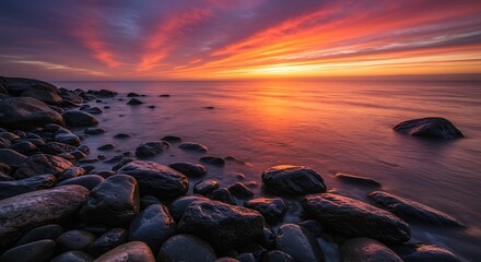 Dramatic Sunset Over Rocky Coastline with Fiery Sky and Calm Water.