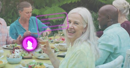 Holding wine glass, white-haired senior smiling at yellow backyard table, purple AR overlay