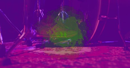 Framing bass drum and pedal with foot in dark shoe pressing on patterned rug, magenta lights