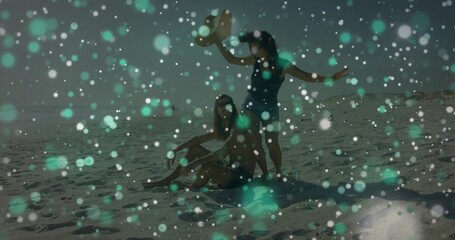 Naklejka premium Sitting couple in dark swimwear soaking sun on sandy beach, with sunhat towel shades teal bokeh