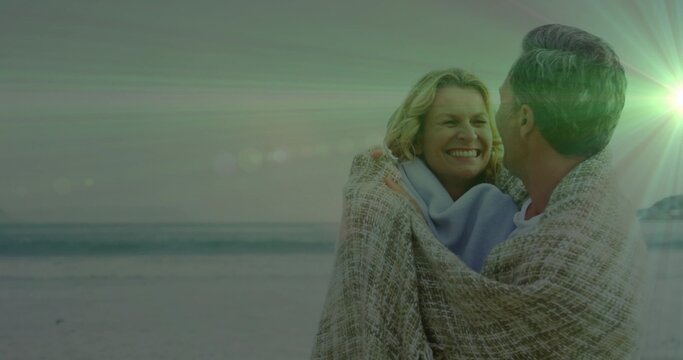 Standing couple embracing, sharing woven blanket on sandy beach with light blue scarf, copy space - Powered by Adobe