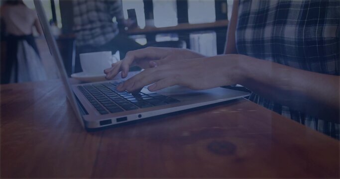 Typing woman wearing short-sleeve plaid shirt at cafe, using laptop with wooden table and cup