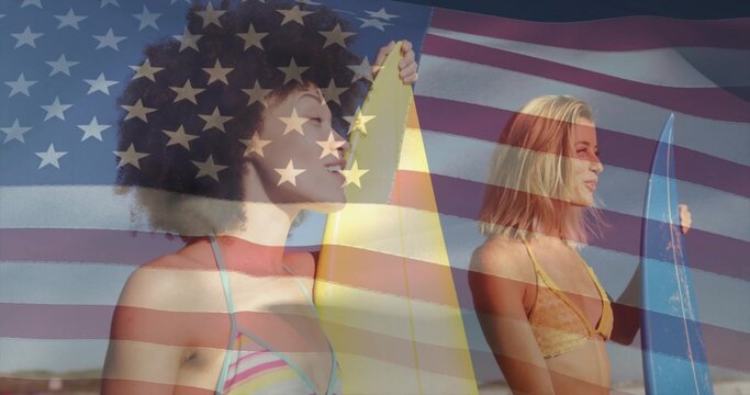 Holding yellow and blue surfboards, two women in bikinis standing on beach, American flag overlay - Powered by Adobe