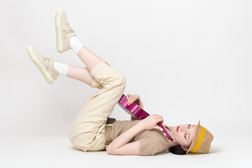 Woman ukulelist plays ukulele with eyes closed while lying on back and legs raised. Carefree and relaxed female musician practices playing stringed musical instrument rehearsing before performance