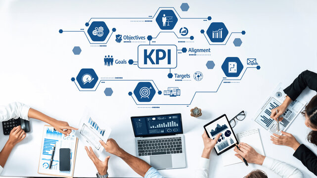 A diverse team collaborates in a modern workspace, analyzing KPI metrics and objectives while using laptops and tablets to enhance business strategies and improve performance. Amity