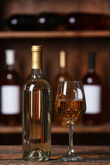 Bottle and glass of exquisite wine on table in cellar