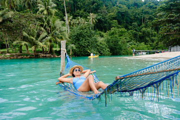 Relaxing in a hammock by the crystal-clear waters of Koh Kood Island Thailand
