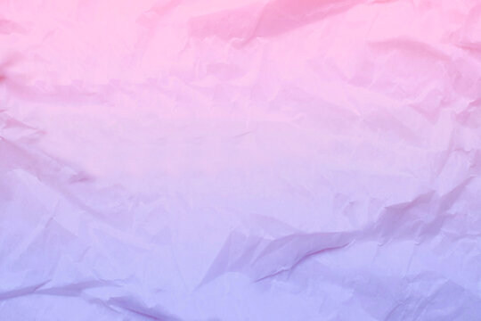 Abstract pastel gradient texture of crumpled paper with a smooth transition from pink to purple. Ideal for backgrounds and design projects.