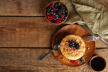 Plate of sweet pancakes with fresh berries and nuts on wooden background