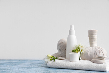 Composition with cosmetic products, spa accessories and flowers on color table against light background