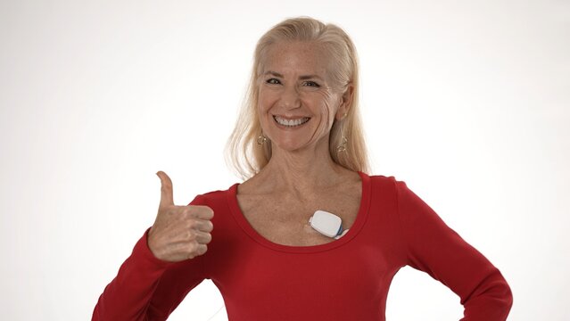 Mature woman shows positive emotion while wearing a heart monitor, promoting awareness of atrial fibrillation and health technology