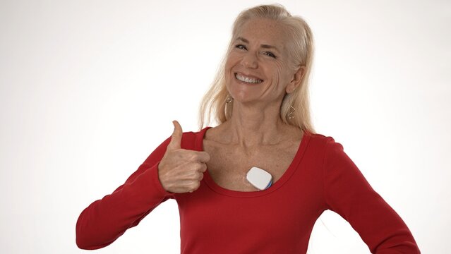 Mature woman with a heart monitor on her chest expresses joy, showcasing technology for tracking atrial fibrillation