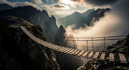 A precarious suspension bridge spans a deep, misty chasm between rugged mountain peaks at sunrise