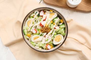 Bowl of salad with crab sticks, corn, iceberg leaves, quail eggs and cucumber on white grunge background