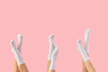 Legs of young women in stylish white socks on pink background