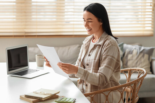 Happy young woman with refund form at table in room