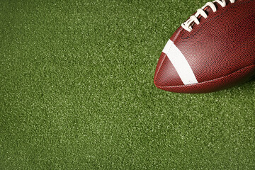 American football ball on green grass as background