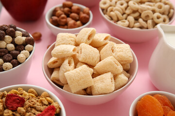 Bowl with corn pillows on pink background, closeup