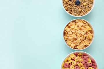 Bowls with different cereals on turquoise background