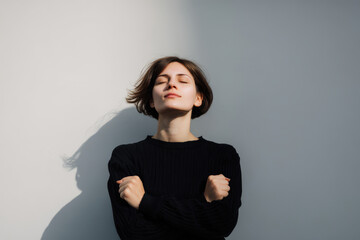 young woman standing with her fists pressed against her chest radiating energy and determination