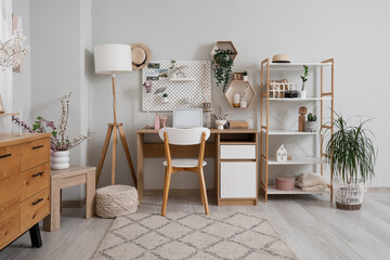 Interior of light office with workplace, pegboard and shelves