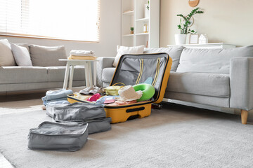 Open suitcase with organizers on carpet in living room interior