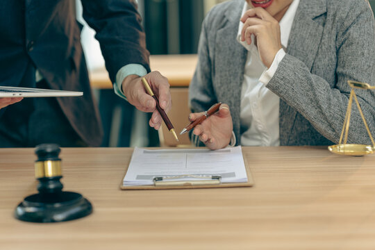 A lawyer in a gray suit is contemplating or considering the law.
With a judge's gavel and a set of golden scales (symbols of justice), this image enhances the legal or courtroom context.