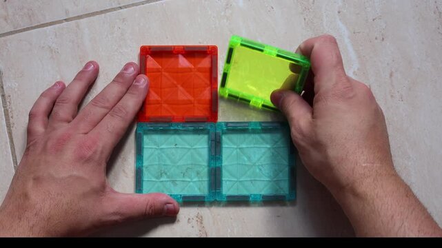 Hands arranging translucent multicolored cube sections into different shapes close-up video concept
