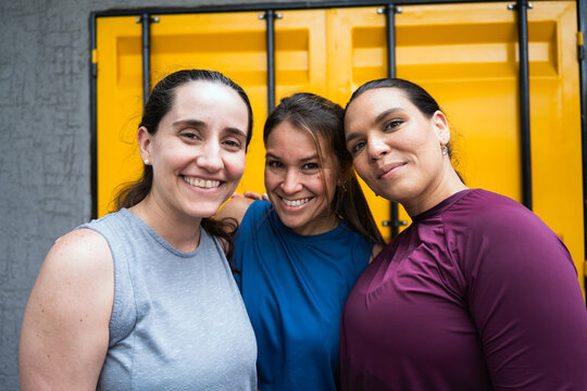 Three happy latin hispanic women friends smiling, enjoying active lifestyle and fitness training outdoors - Powered by Adobe