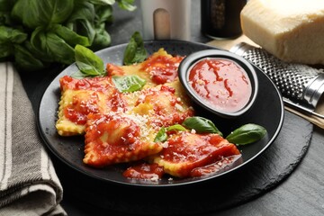 Delicious ravioli with tomato sauce, cheese, grater and basil on grey table, closeup
