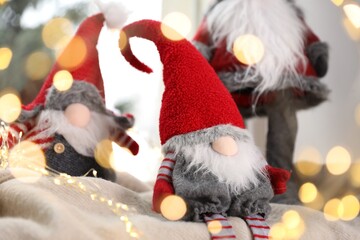 Naklejka premium Christmas gnomes on blanket near window at home, closeup. Bokeh effect